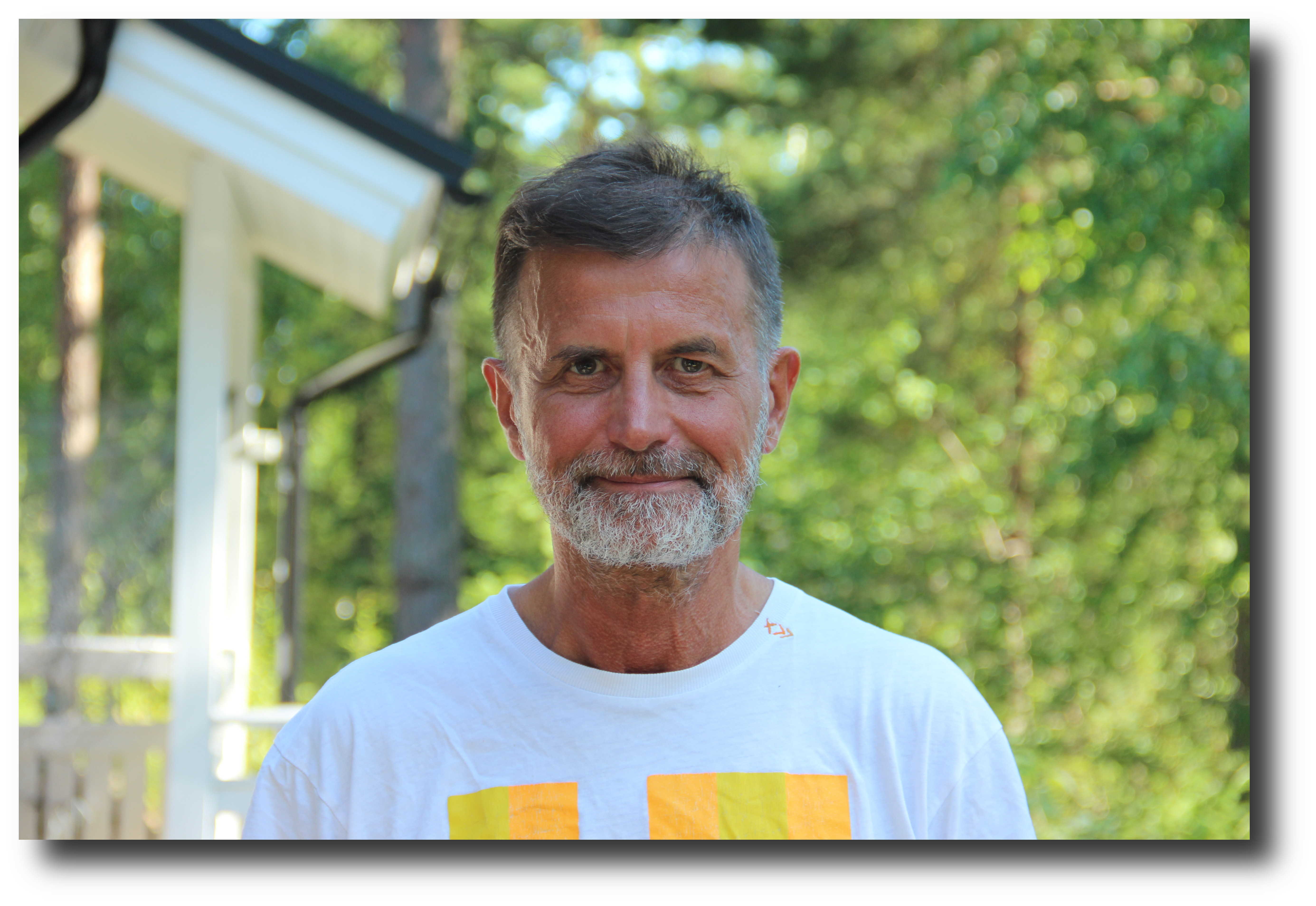 Jeanine White smiling in a red plaid shirt and tortoise shell glasses